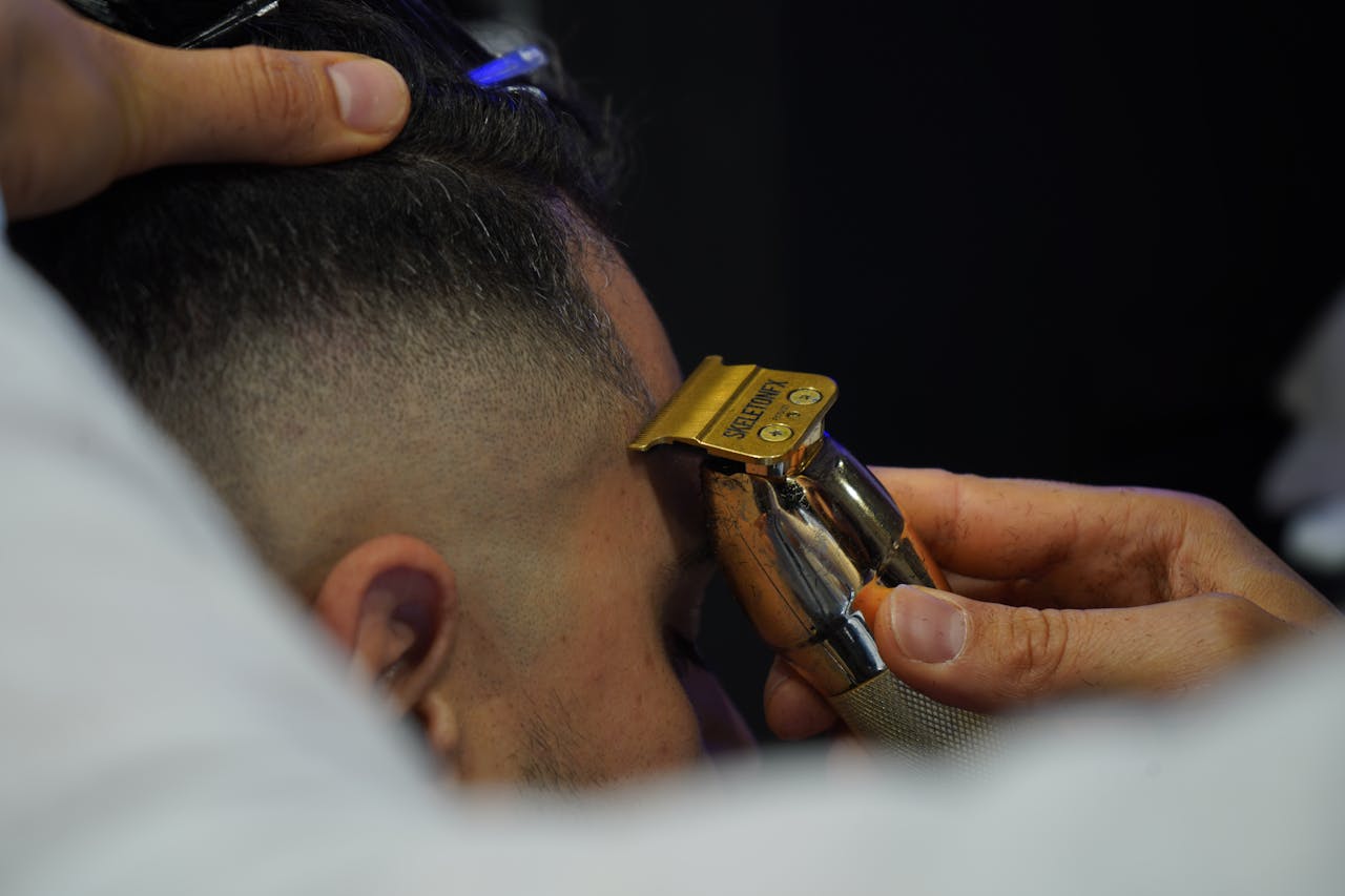 Close-up of a barber using an electric razor for precise grooming on a client's temple.