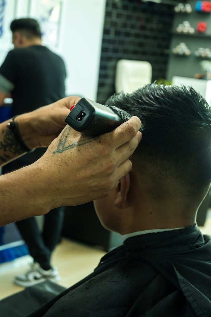 Close-up of a barber using clippers to trim a client's hair in a modern salon setting.