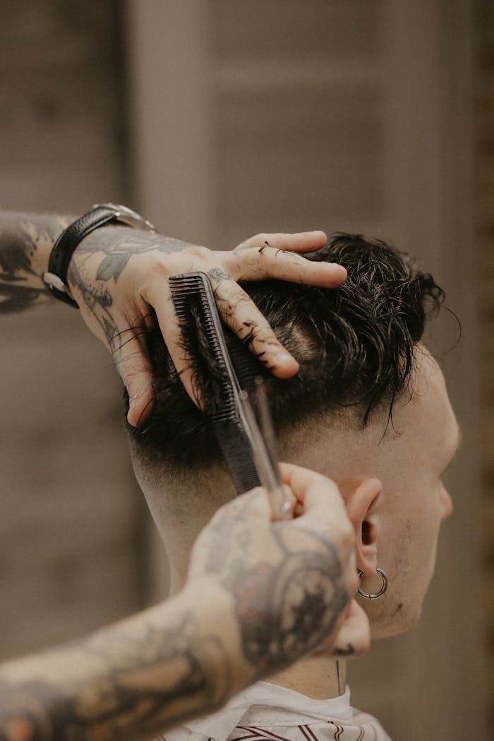 A barber with tattoos trims a man's hair with precision in a Belarusian barber shop.