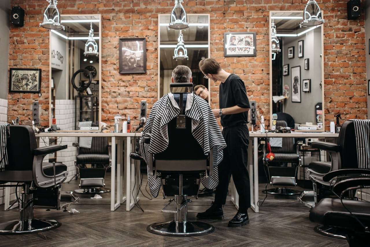 A skilled barber attending to a client in a stylish barbershop with exposed brick walls.
